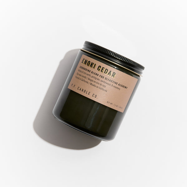 P.F. Candle Co. Enoki Cedar Alchemy Candle - Product - Alchemy Candles feature smoke-colored glass vessels, black metal lids, and gold-leafed labels inspired by vintage window lettering.