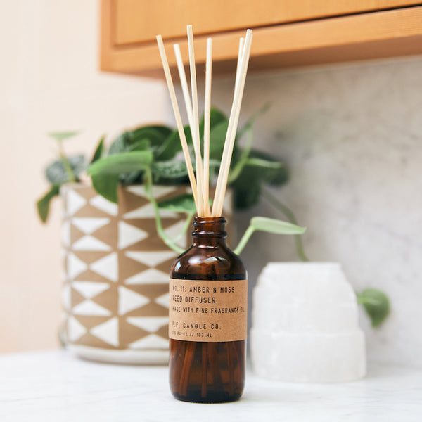 P.F. Candle Co. Amber & Moss Reed Diffuser - Lifestyle - Scent notes of sage, moss, and lavender. Inspired by a weekend in the mountains, sun gleaming through the canopy.