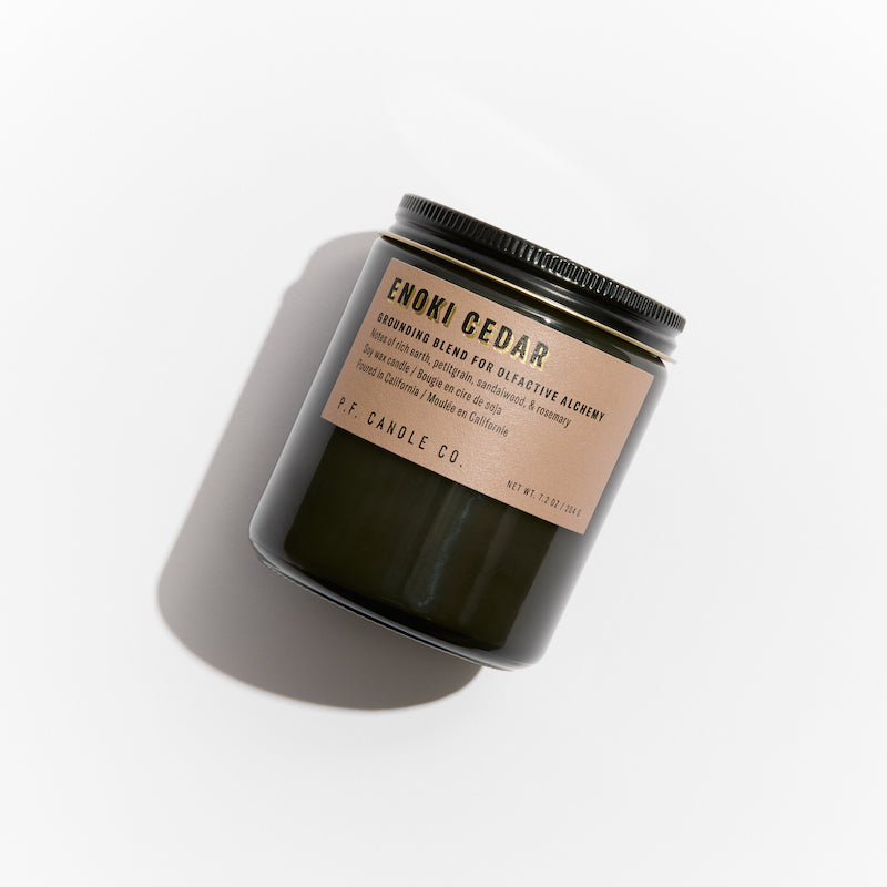 P.F. Candle Co. Los Angeles - Enoki Cedar Alchemy 7.2 oz Standard Scented Soy Wax Candle - Product - Alchemy Candles feature smoke-colored glass vessels, black metal lids, and gold-leafed labels inspired by vintage window lettering.