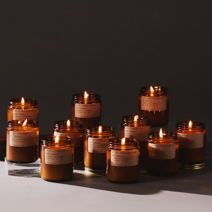 Set of lit pf candle co candles with labels on a dark background