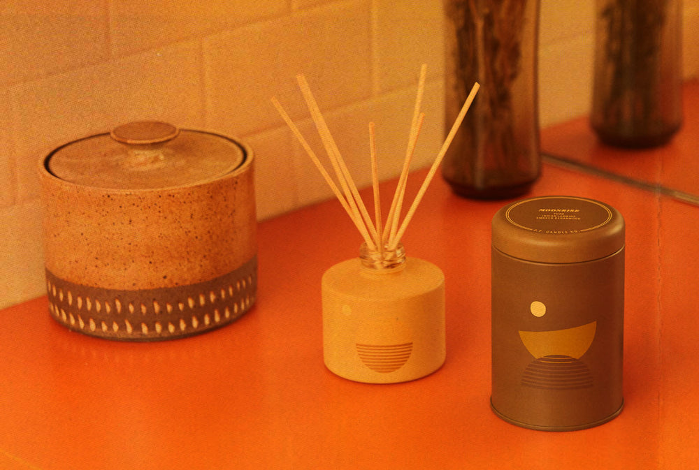 The P.F. Candle Co. Los Angeles - P.F. Over The Years - 2019: A New Line. We added the Sunset Line inspired by 1970s summers in California. The design was totally new, featuring unique vessel colors with cheerful motifs. Sunset Line Golden Hour Reed Diffuser and Moonrise Candle