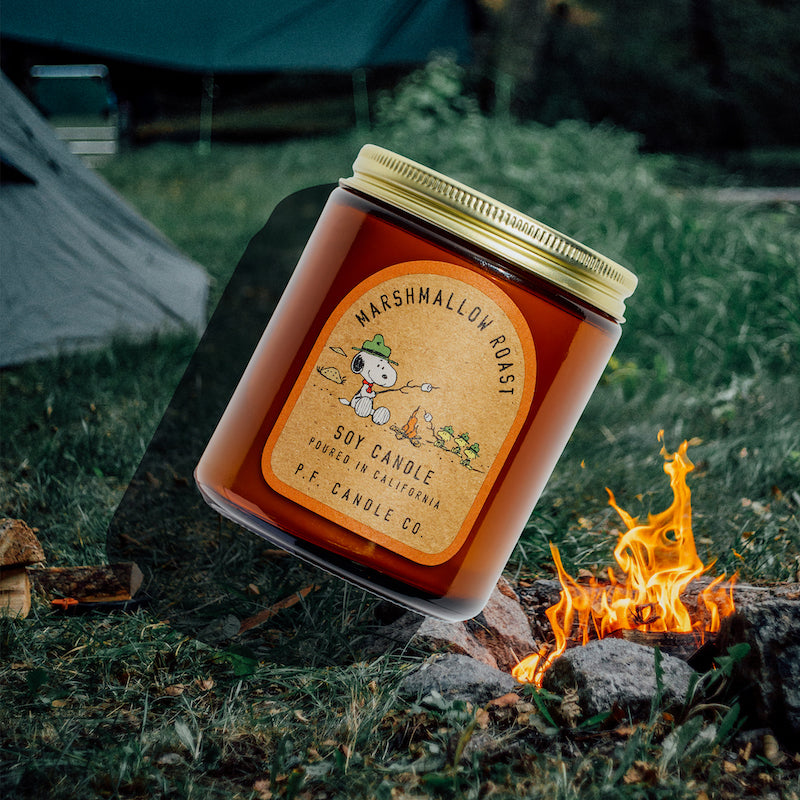 P.F. Candle Co. Marshmallow Roast for Peanuts Standard Candle - Lifestyle -  Inspired by late-night bonfires with buds, deep conversation under the cosmos, and the beloved s’more, Marshmallow Roast is an earthy take on the beloved treat, featuring notes of sweet lemon, cedar logs, and vanilla to bring warmth to nights spent catching up with comrades.  