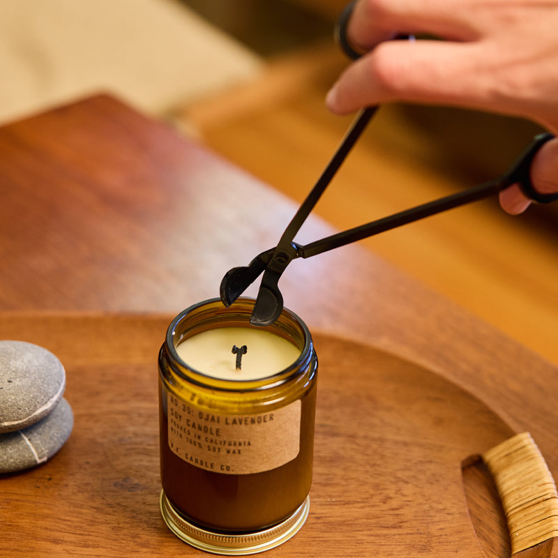 Candle being trimmed by wick trimmer