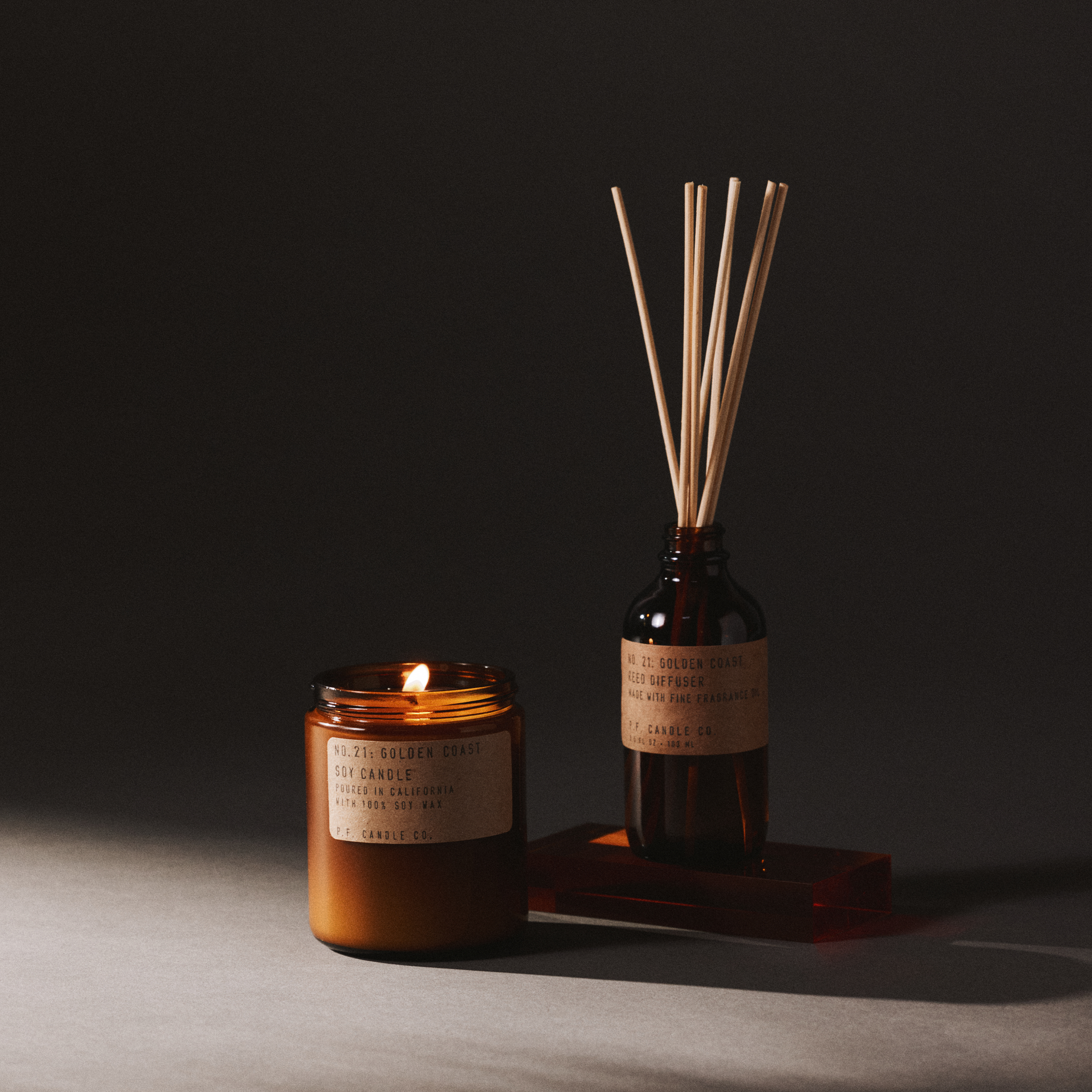 golden coast candle and reed diffuser set on a dark background