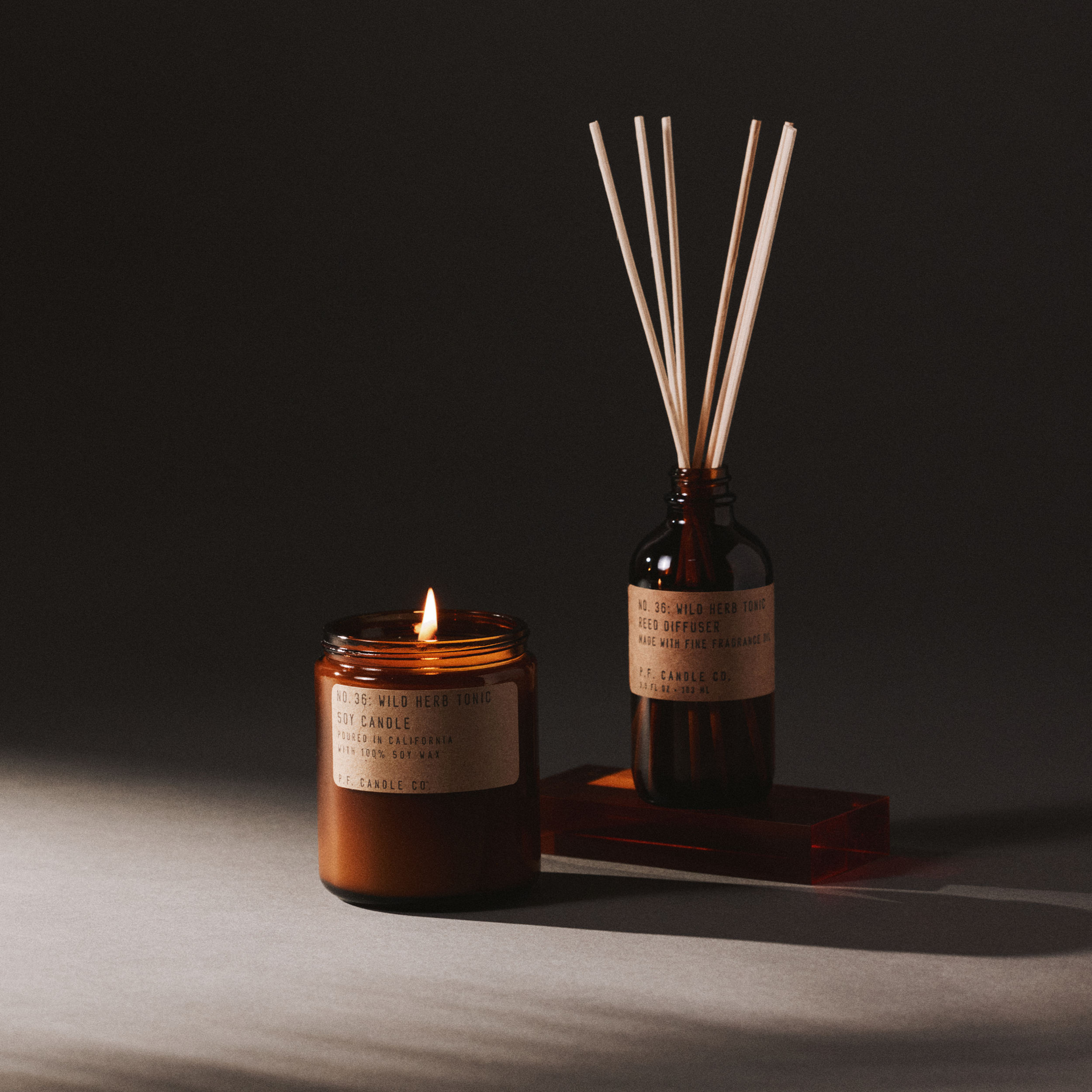 wild herb candle and reed diffuser set on a dark background