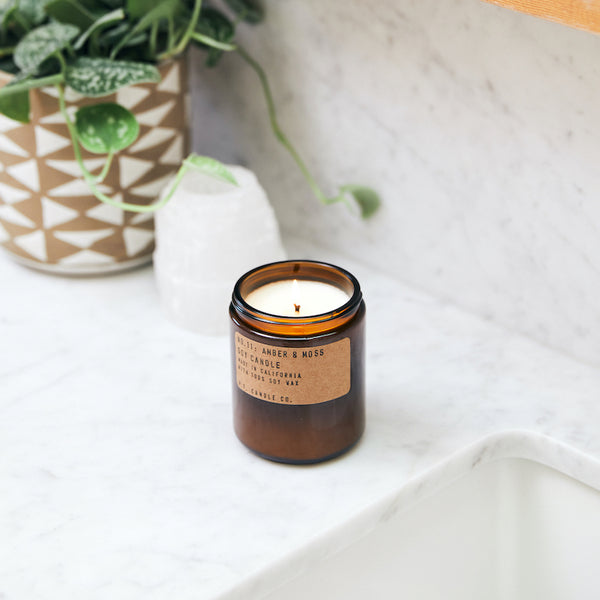 P.F. Candle Co. Amber & Moss Standard Candle - Lifestyle - Scent notes of sage, moss, and lavender. Inspired by a weekend in the mountains, sun gleaming through the canopy.
